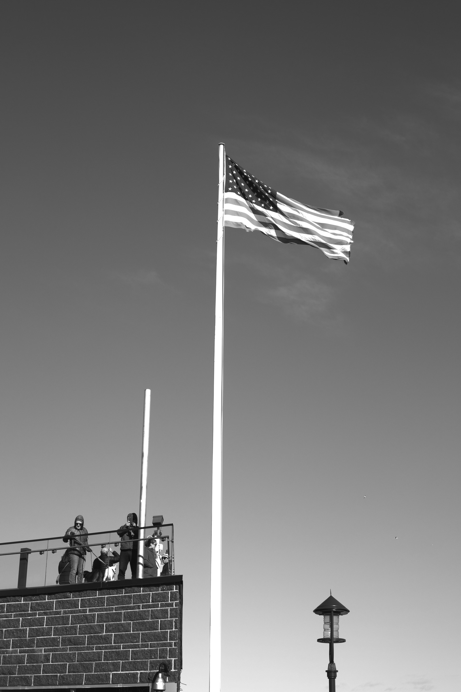 People standing beneath an American flag beside the waterfront.