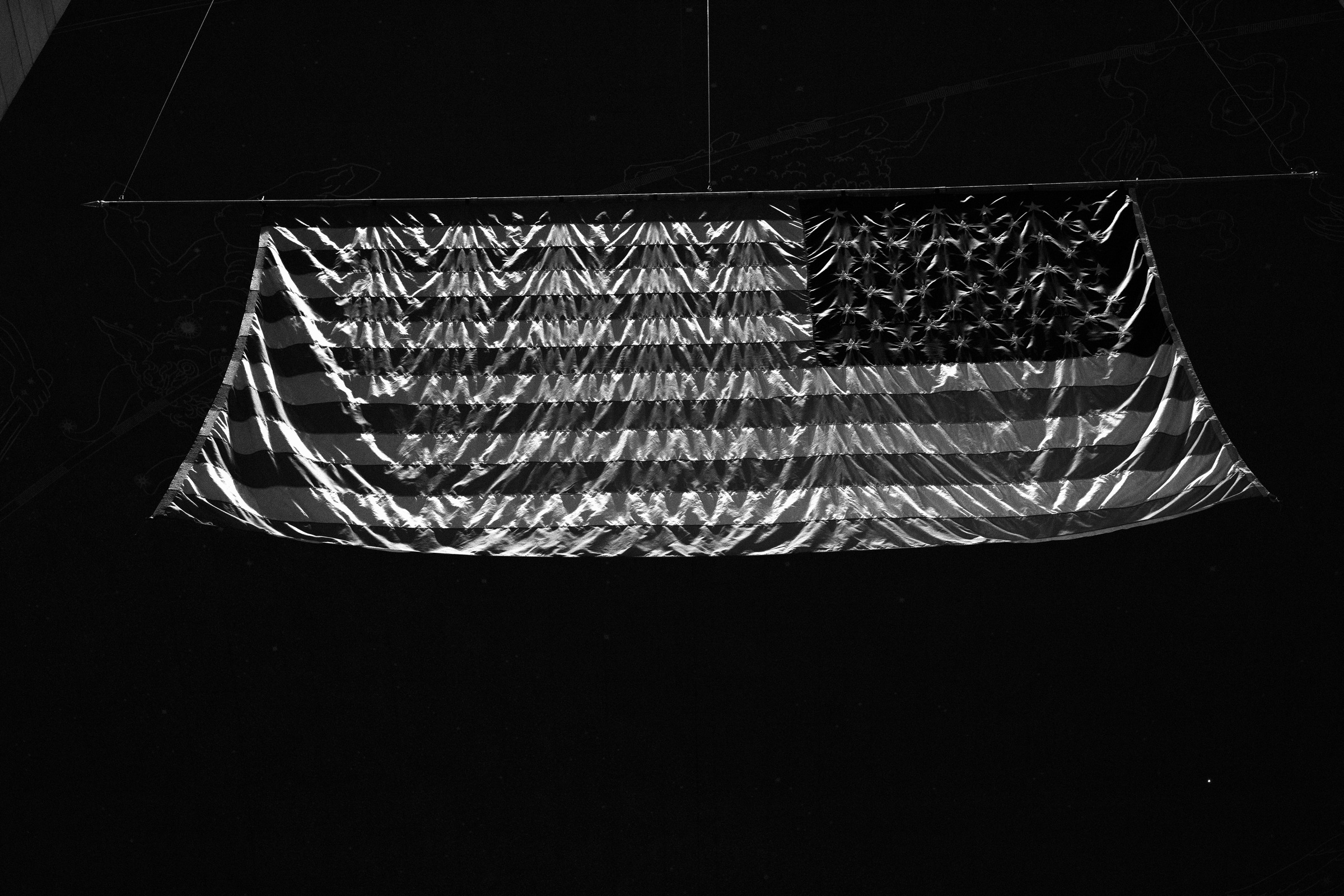 An American flag suspended in a dark interior.