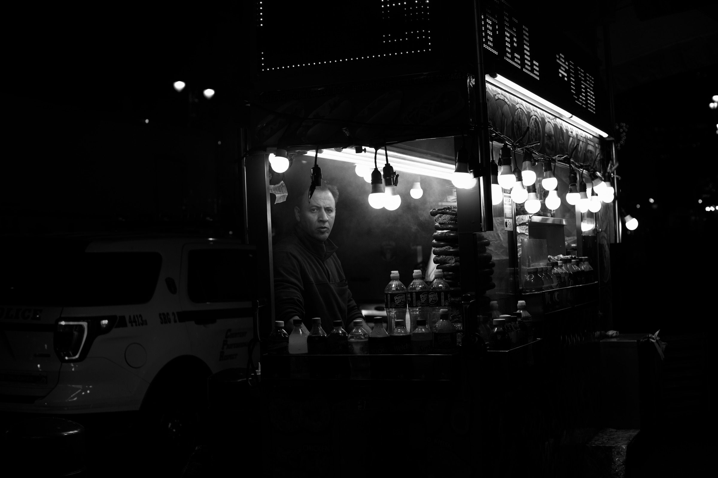 A softly illuminated storefront and passing figures at night.