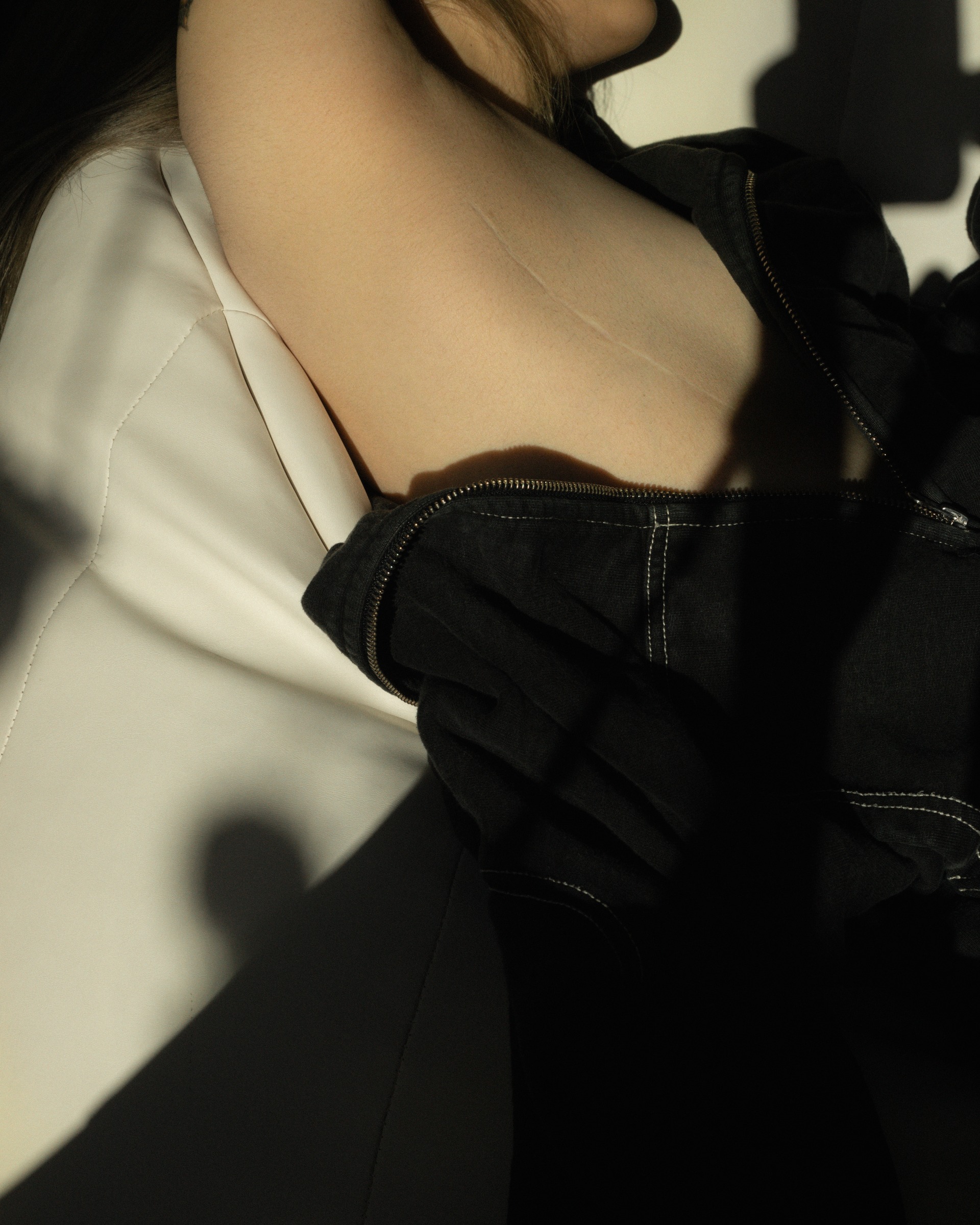 A close view of a body in black clothing, with light falling across the chest.