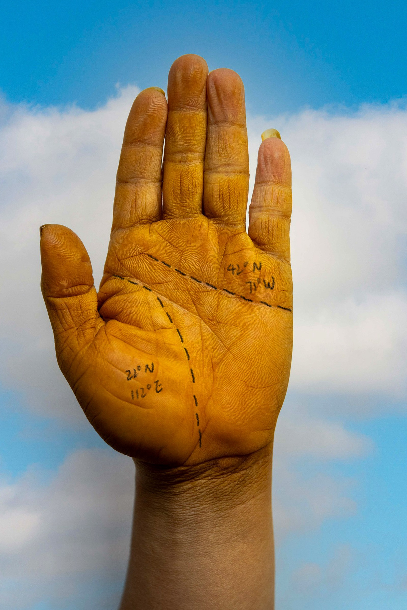 An open palm marked with handwriting against a blue sky.