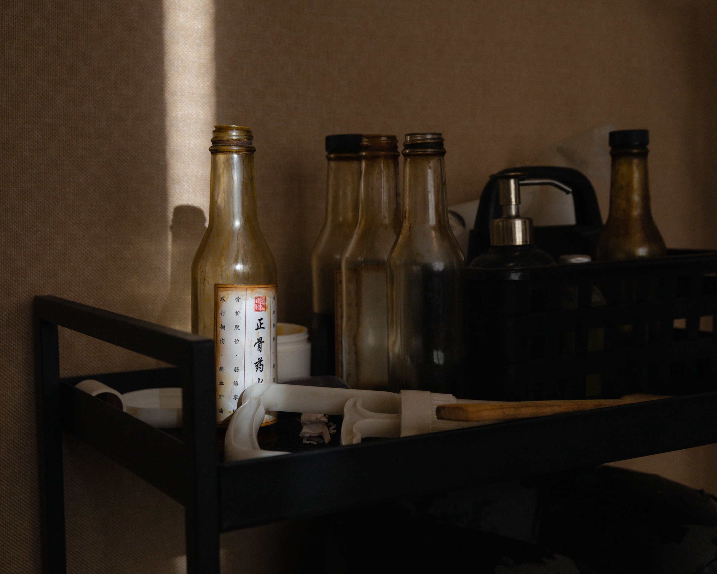 Bottles and a kettle in a dimly lit interior.